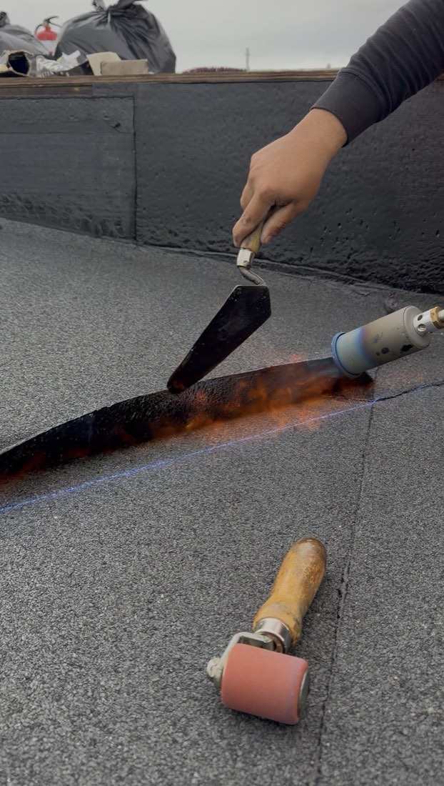 Bitumen membrane being heat-bonded to a flat roof with a torch